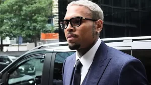 Chris Brown in a blue suit arriving at Southwark Crown Court, walking past photographers and fans outside the building.