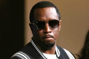 Sean “Diddy” Combs seated in a courtroom, wearing a dark suit with a solemn expression during his trial.