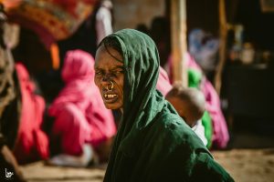 A UN official walks through a war-ravaged neighborhood in Khartoum, Sudan, where buildings are destroyed and debris lines the streets.