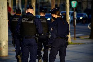 French police patrolling at night in a city enforcing youth curfew due to drug violence.