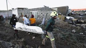 A flooded rural road in Eastern Cape, with rescue teams navigating debris and stranded locals.