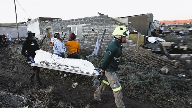 A flooded rural road in Eastern Cape, with rescue teams navigating debris and stranded locals.