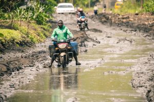 Flooded street in Kinshasa with submerged houses and stranded residents after heavy rainfall.