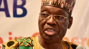 Issa Tchiroma Bakary addressing a crowd with a raised fist, symbolizing his break from Paul Biya’s long-standing regime in the lead-up to Cameroon’s presidential election.