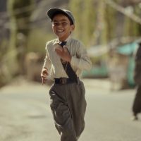 A young teenage boy walking alone with a school bag, symbolizing separation and forced relocation.