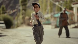 A young teenage boy walking alone with a school bag, symbolizing separation and forced relocation.