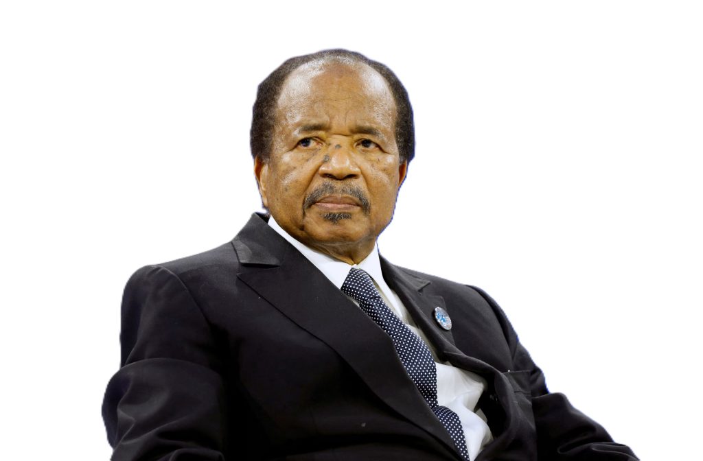 Cameroon President Paul Biya at a formal event, seated and wearing a dark suit with a stern expression.