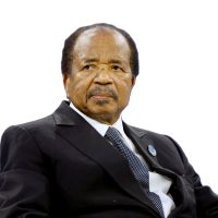 Cameroon President Paul Biya at a formal event, seated and wearing a dark suit with a stern expression.