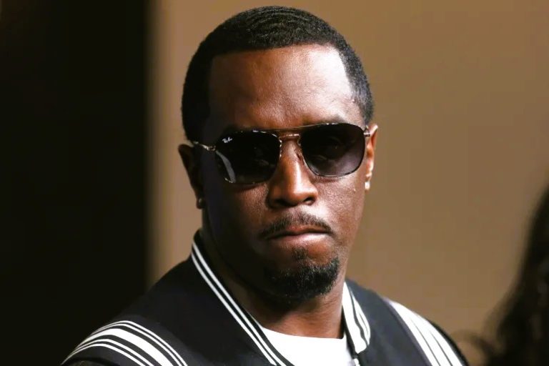 Sean “Diddy” Combs seated in a courtroom, wearing a dark suit with a solemn expression during his trial.