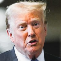 Former US President Donald Trump speaks at press conference announcing new tariff policy with US flags in the background.
