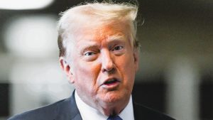 Former US President Donald Trump speaks at press conference announcing new tariff policy with US flags in the background.