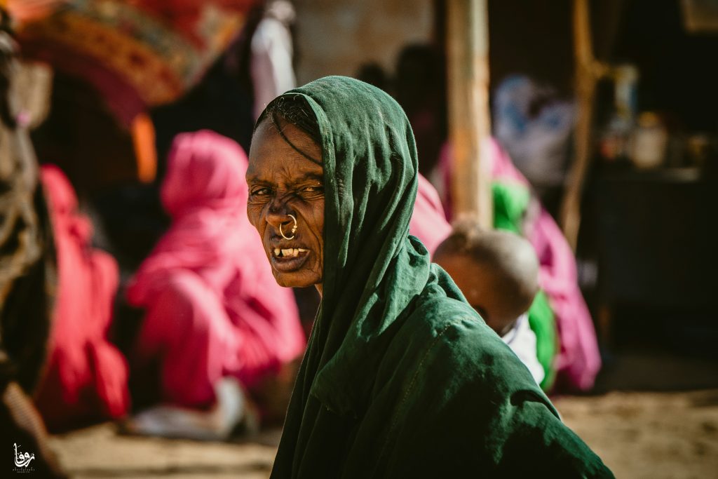 A UN official walks through a war-ravaged neighborhood in Khartoum, Sudan, where buildings are destroyed and debris lines the streets.